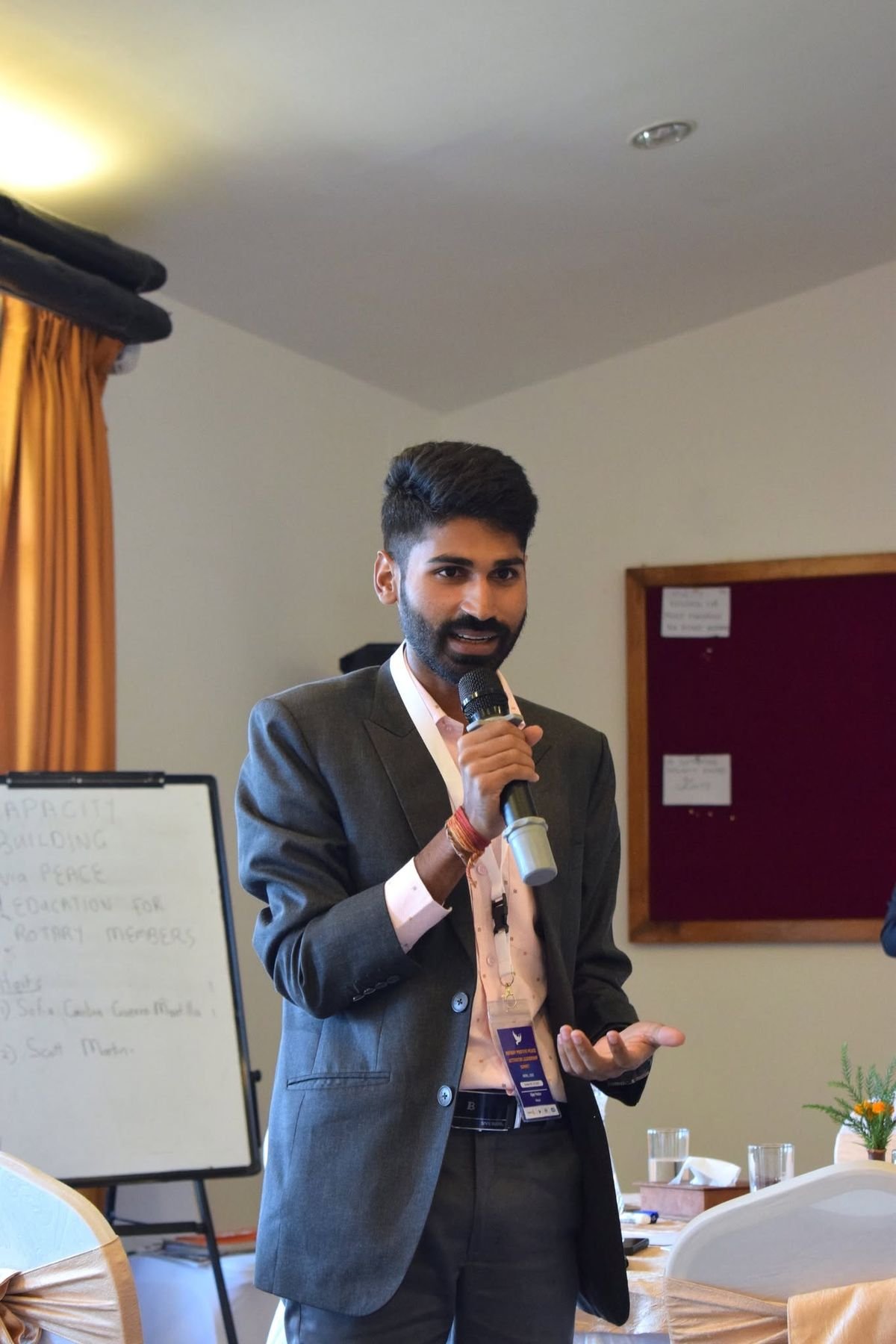 Ajay facilitating with a microphone beside a flip chart.