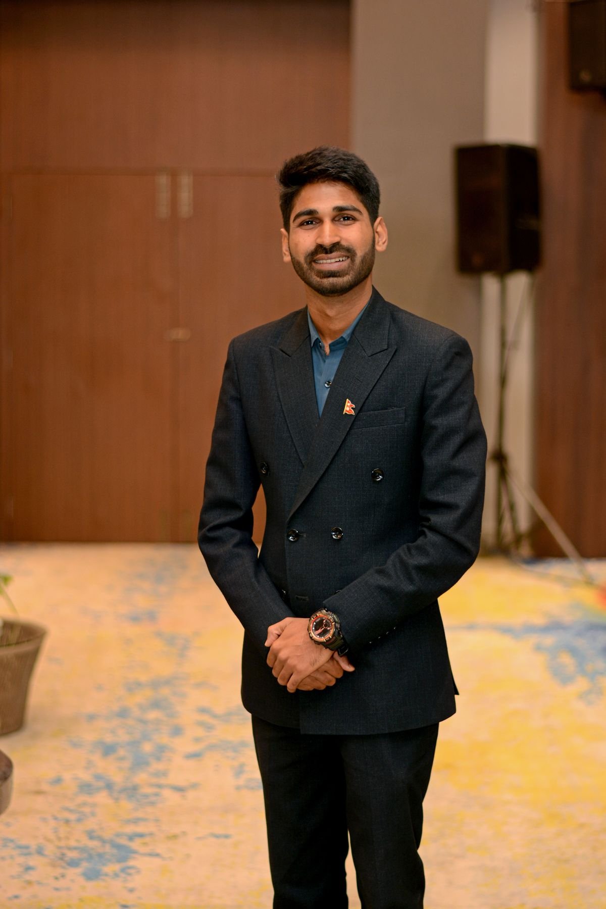 Portrait of Ajay Yadav standing, hands clasped, in a warm room.