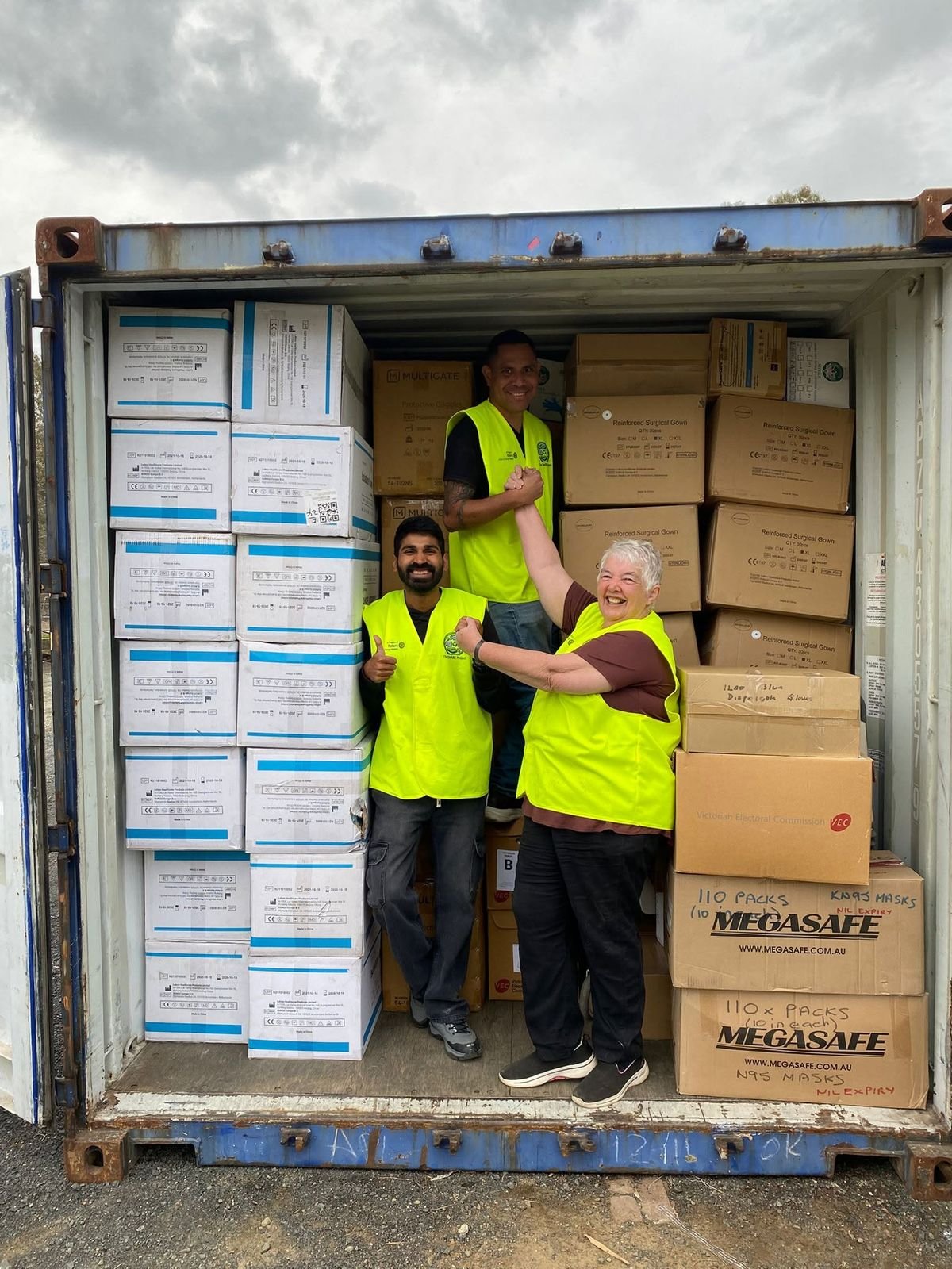 Volunteers in high visibility vests loading boxes inside a shipping container.