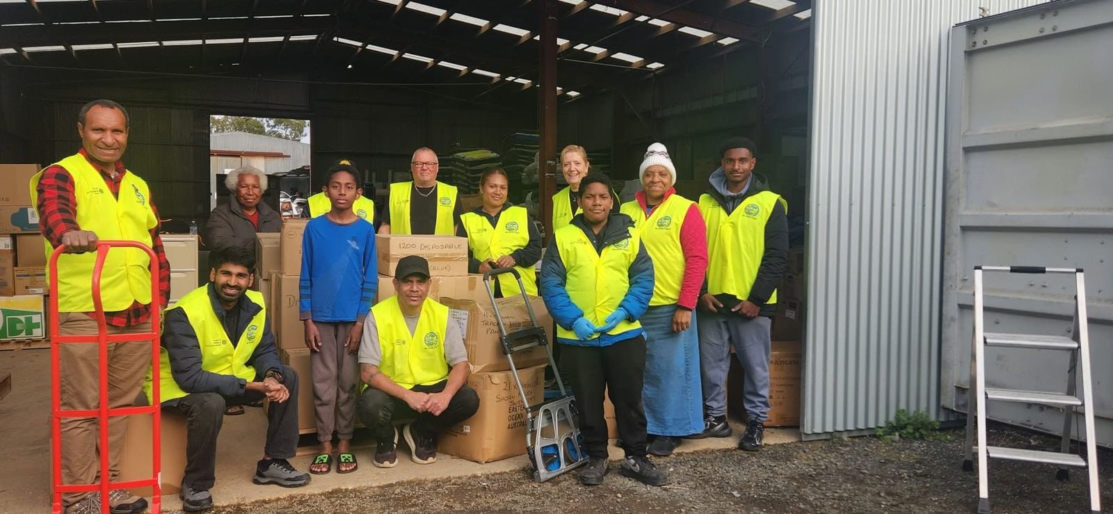 A group of volunteers in high visibility vests posing together in a warehouse.